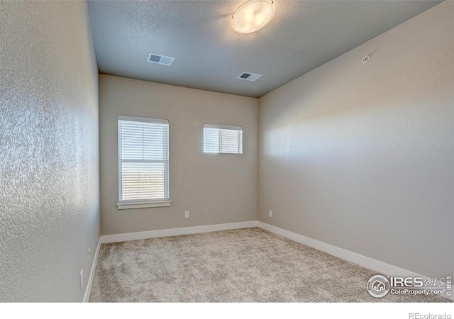 carpeted spare room with a textured ceiling