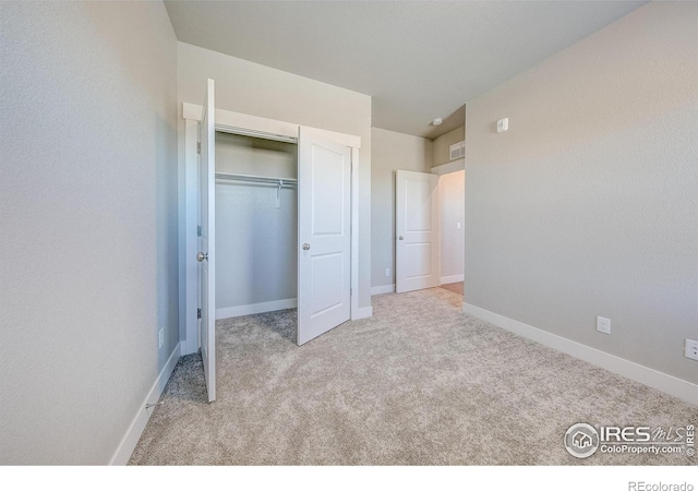 unfurnished bedroom featuring light carpet and a closet