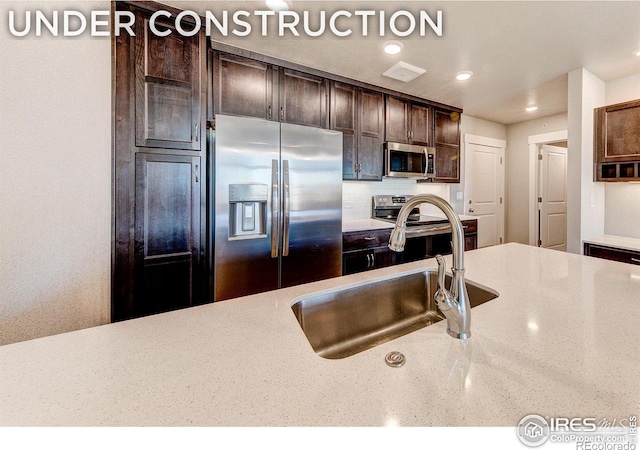 kitchen featuring backsplash, dark brown cabinetry, sink, and appliances with stainless steel finishes