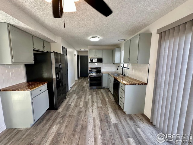 kitchen featuring ceiling fan, sink, wood-type flooring, a textured ceiling, and appliances with stainless steel finishes