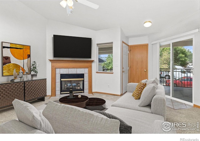 carpeted living room with a tiled fireplace, plenty of natural light, and ceiling fan