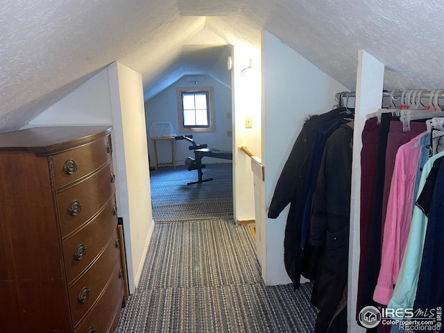 hallway with a textured ceiling, carpet, and vaulted ceiling