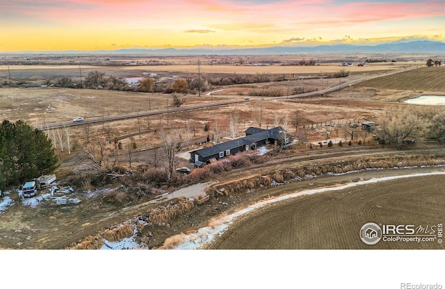 aerial view at dusk featuring a rural view and a mountain view