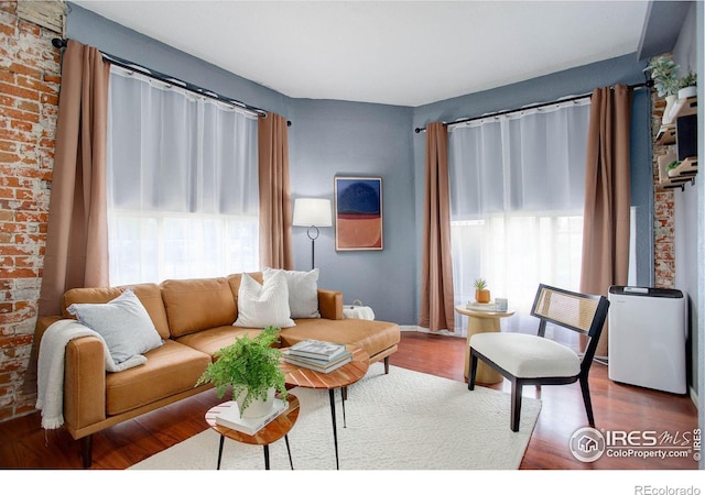 living room with hardwood / wood-style floors and brick wall