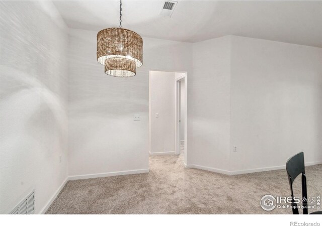 unfurnished dining area featuring a notable chandelier, visible vents, and light colored carpet