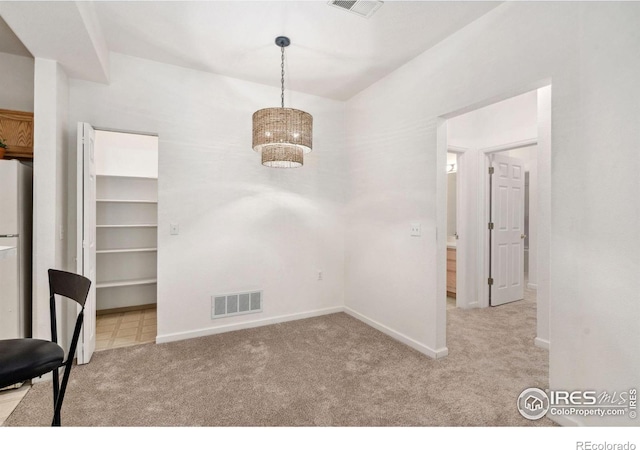 unfurnished dining area featuring light carpet, visible vents, and baseboards