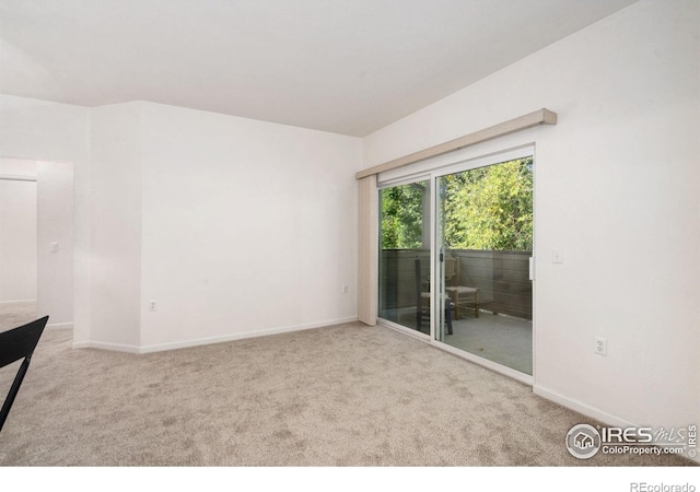 empty room featuring light carpet and baseboards