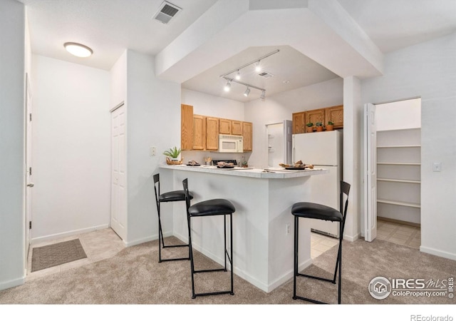 kitchen featuring light carpet, light countertops, white appliances, and a breakfast bar