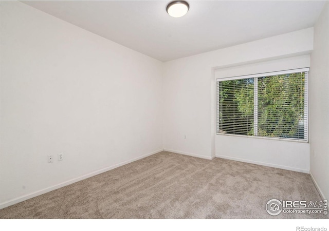 unfurnished room with light carpet and baseboards