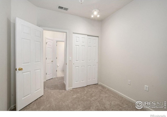 unfurnished bedroom featuring baseboards, visible vents, a closet, and light colored carpet