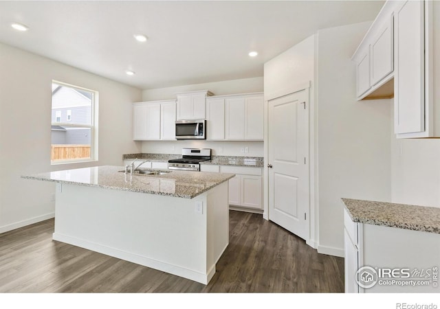 kitchen with appliances with stainless steel finishes, a center island with sink, white cabinetry, and sink