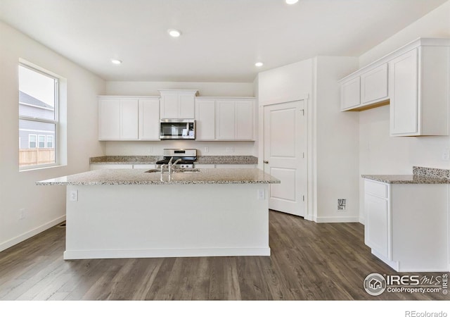 kitchen with white cabinetry, stainless steel appliances, and an island with sink