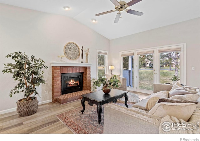 living room with a fireplace, light hardwood / wood-style floors, ceiling fan, and lofted ceiling