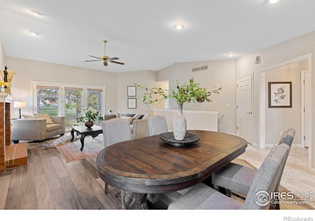 dining area with light wood-type flooring, vaulted ceiling, and ceiling fan