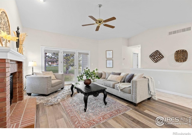 living room featuring hardwood / wood-style flooring, ceiling fan, a fireplace, and vaulted ceiling