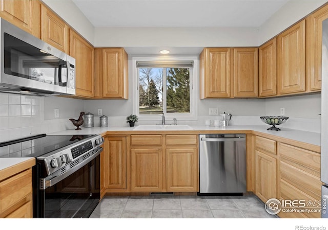 kitchen featuring decorative backsplash, sink, light tile patterned floors, and stainless steel appliances