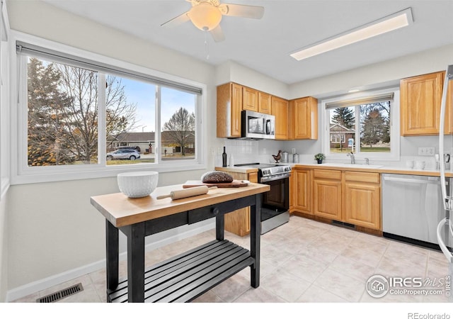 kitchen with decorative backsplash, stainless steel appliances, light tile patterned flooring, and sink