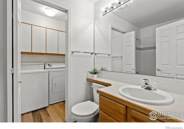 bathroom featuring washer and clothes dryer, vanity, toilet, and hardwood / wood-style floors