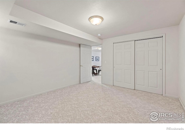 unfurnished bedroom featuring light carpet and a closet