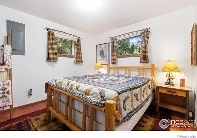 bedroom with electric panel, hardwood / wood-style flooring, and multiple windows