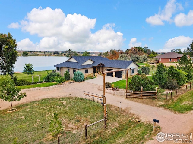 view of front of property with a garage, a front lawn, a rural view, and a water view