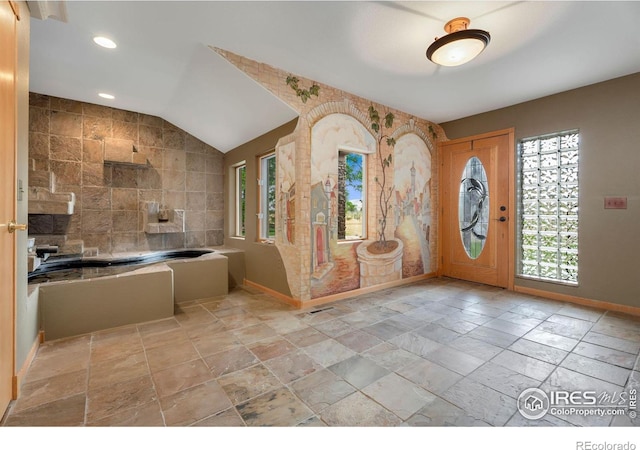 foyer featuring lofted ceiling and tile walls