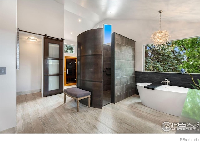 bathroom with a bathtub, lofted ceiling, an inviting chandelier, tile walls, and wood-type flooring