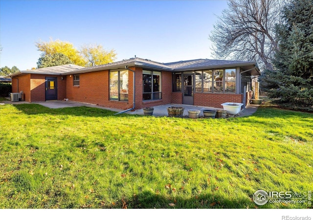 back of house featuring a yard, a patio, and a sunroom