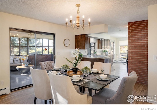 dining area with light hardwood / wood-style flooring, a textured ceiling, and a notable chandelier