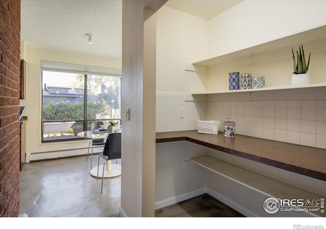 interior space with tasteful backsplash, a textured ceiling, a baseboard radiator, and brick wall