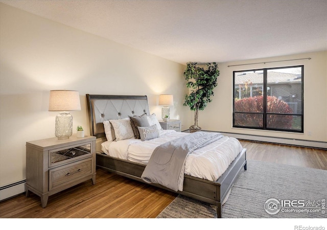 bedroom featuring a textured ceiling, light hardwood / wood-style floors, and baseboard heating