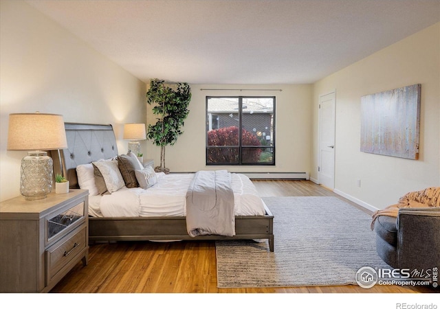 bedroom with baseboard heating and light hardwood / wood-style floors