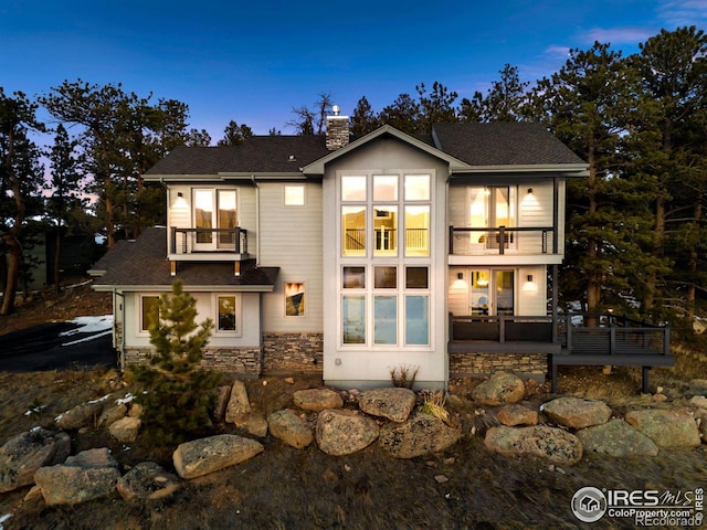 back house at dusk with a balcony