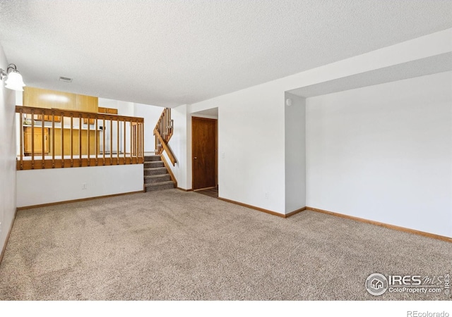 carpeted empty room with a textured ceiling