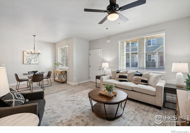 living room with ceiling fan with notable chandelier and light wood-type flooring