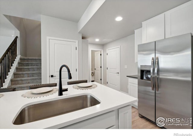 kitchen featuring white cabinets, stainless steel fridge with ice dispenser, light hardwood / wood-style floors, and sink