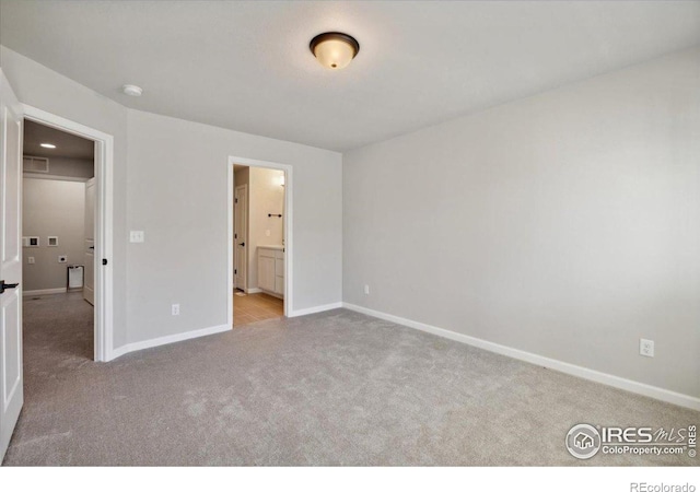 unfurnished bedroom featuring ensuite bathroom and light carpet