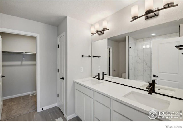 bathroom with vanity, a textured ceiling, and tiled shower