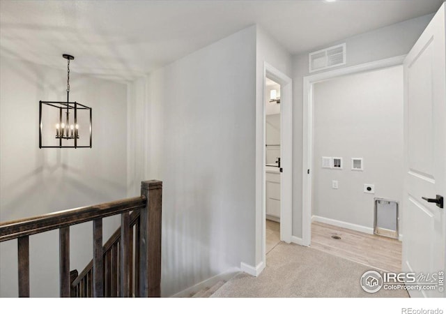 hall with light hardwood / wood-style floors and a notable chandelier