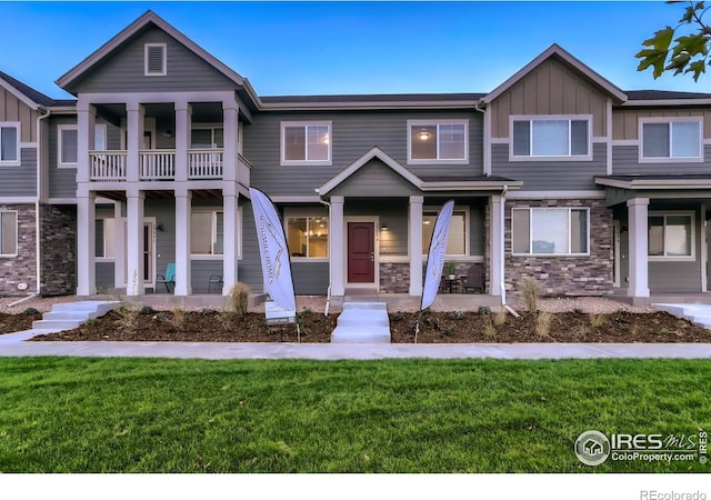 view of front of home featuring a balcony, covered porch, and a front yard