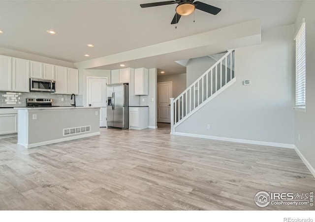 kitchen featuring light hardwood / wood-style floors, white cabinetry, an island with sink, and appliances with stainless steel finishes