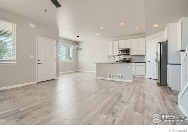 kitchen featuring white cabinets, appliances with stainless steel finishes, a center island, and a wealth of natural light