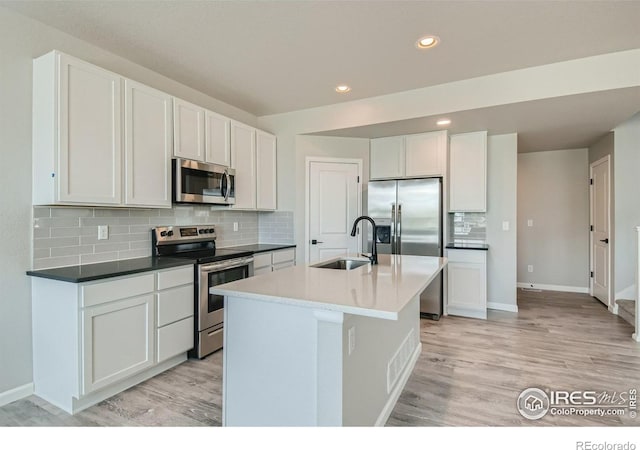 kitchen with sink, white cabinets, stainless steel appliances, and light hardwood / wood-style floors