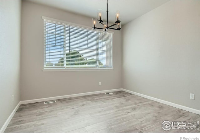 spare room with a chandelier and light hardwood / wood-style floors