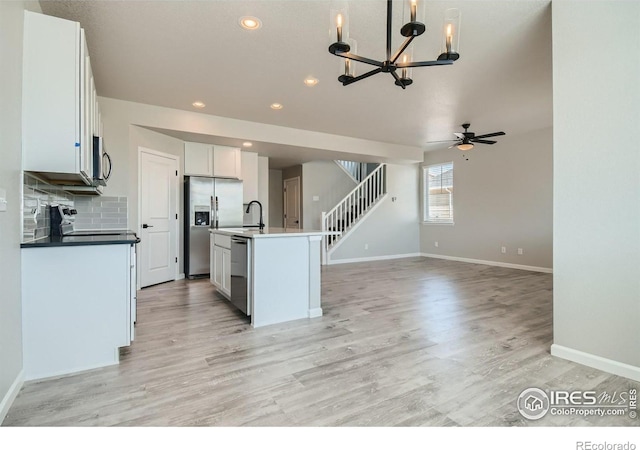 kitchen with a kitchen island with sink, hanging light fixtures, light hardwood / wood-style floors, white cabinetry, and stainless steel appliances