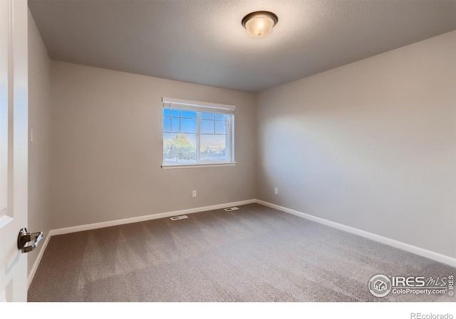 carpeted spare room featuring a textured ceiling