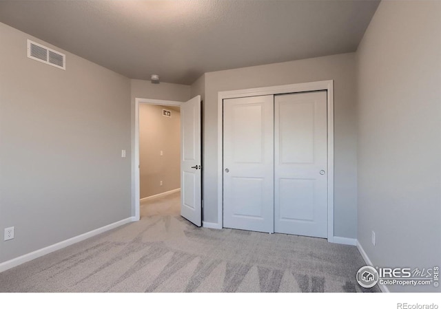 unfurnished bedroom with light colored carpet and a closet