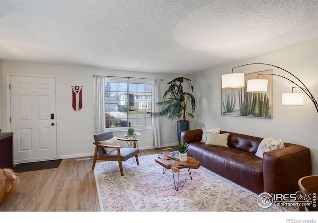 living room with a textured ceiling and light hardwood / wood-style flooring