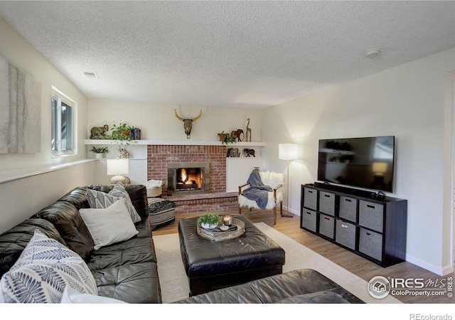 living room with a fireplace, light hardwood / wood-style floors, and a textured ceiling