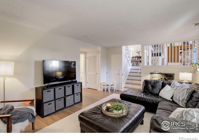 living room featuring light wood-type flooring and a textured ceiling